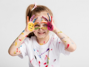 Little girl covered in paint making funny faces.